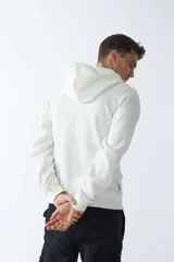 Campera de felpa color blanco hueso, con capucha y cordón ajustable, cierre frontal con cremallera, bolsillos laterales, logo y arte estampado en el pecho.