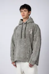 Buzo canguro oversize de algodón friza con efecto de teñido artesanal desgastado. Presenta capucha con cordones negros, bolsillo frontal tipo canguro y estampa pequeña de Popeye en el pecho.