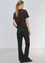 Camiseta marrón de algodón con cuello redondo y manga corta, con estampa frontal azul de flores y texto "Bloom More Worry Less".
