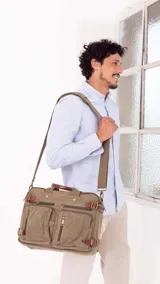 Mochila porta notebook color verde oliva de tela canvas con detalles en cuero marrón. Tiene múltiples bolsillos con cierre y correas ajustables.