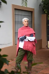 Ruana de lana merino tejida en telar, con diseño de rayas verticales en tonos crudo y rojizo, y terminación de flecos en el ruedo.