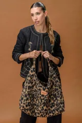 Bolso tipo hobo de gran capacidad con estampado animal print de vaca en tonos marrón y blanco. Presenta una etiqueta de cuero con el logo de la marca en el frente y un diseño de caída relajada.