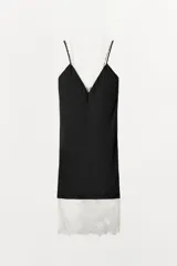 Vestido midi de satén negro con escote en pico y tirantes finos. Presenta detalles de encaje blanco a contraste en el escote y en el ruedo.