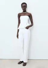 Top peplum blanco sin mangas, con escote palabra de honor y diseño ajustado en el torso con vuelo en el bajo.