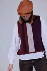 Chaleco de tejido de punto con diseño de bloques de color en tonos tierra, incluyendo marrón, verde oliva y beige. Presenta un panel central con textura tejida y cuello redondo.