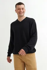 Sweater de punto color negro con cuello en V, mangas largas y puños acanalados.