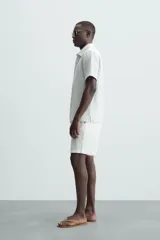 Bermuda azul marino de corte regular fit, confeccionada en tejido de algodón y lino. Cuenta con bolsillos frontales y traseros, cierre frontal con cremallera y botón.