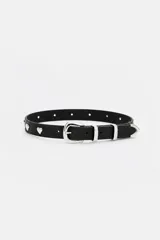 Cinturón de cuero vacuno negro con hebilla, pasadores y puntera metálicos plateados, decorado con apliques de tachas en forma de corazón.
