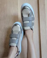 Zapatillas urbanas de cuero color beige y gris metalizado con cierre de doble velcro, detalle animal print en el talón y suela chunky blanca.