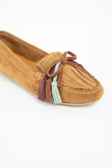 Mocasin de gamuza color camel, con detalle de flecos decorativos en la parte frontal en tonos marrón, violeta y verde agua.