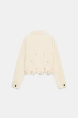 Cazadora color rosa pálido, de cuello solapa y manga larga. Tiene bordados perforados a tono en el ruedo y cierre frontal con botones color madera.