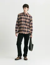 Camisa de franela con estampado de cuadros escoceses en tonos marrones, azules y blancos. Presenta cuello button-down, manga larga y cierre frontal con botones de madera.