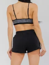 Set de top negro con brillos y tirantes regulables, combinado con short negro de cintura elástica con cordón de ajuste.