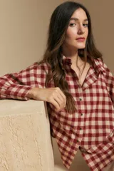 Camisa de estilo leñador con estampado de cuadros en tonos azul, negro y marrón. Presenta cuello clásico, cierre frontal con botones y mangas largas con puños abotonados.