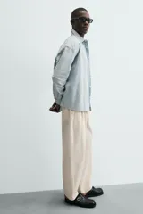 Camisa de denim de algodón, color celeste claro lavado, de corte relajado (relaxed fit) con cuello solapa, manga larga terminada en puño con botón y cierre frontal de botonadura. Presenta un pequeño bordado a contraste en el pecho.