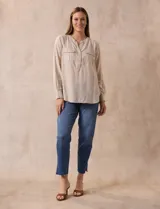 Blusa color beige de lino, marca Dash. Cuello a la base, escote en V y abertura con botones. Delantera con bolsillos. Largo de manga regulable con presilla y botón.