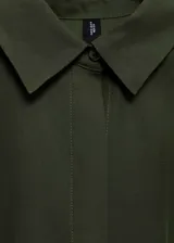 Vestido midi de corte evasé en color verde oliva, con cuello camisero, cierre frontal de botones y mangas cortas con dobladillo. Incluye un cinturón de la misma tela para ajustar a la cintura y detalle de pinzas delanteras.