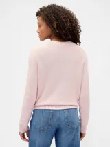 Buzo de algodón color crema con cuello redondo y diseño de punto trenzado en el frente.