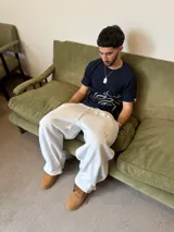 Pantalón de jogging gris melange de corte baggy, confeccionado en algodón. Presenta cintura elástica con cordón largo ajustable, bordado decorativo en la pierna izquierda y botones metálicos en la parte inferior de la botamanga para ajustar el ancho.