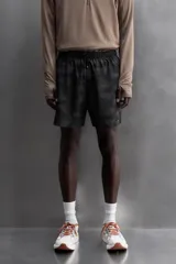 Short deportivo negro con estampado abstracto, cintura elástica ajustable con cordón, bolsillos laterales y trasero con cierre, forro interior y detalle de perforaciones en el ruedo.