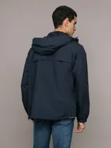 Campera rompeviento Calvin Klein de color azul marino, con cierre frontal de cremallera, capucha ajustable y bolsillos laterales. Presenta un parche con el logo de la marca en la manga y puños elásticos.