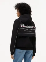 Cortavientos negro con capucha fija, cierre frontal de cremallera con cinta distintiva y puños elásticos. Presenta logos de la colaboración Cadillac Formula 1 Team en el pecho y diseño de corte regular.