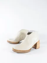 Botas cortas color crema con textura simil cuero de reptil, con cierre lateral y taco de madera.