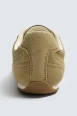 Zapatilla de estilo retro con cordones, confeccionada en una combinación de piezas de tela y cuero con acabado de gamuza. Cuenta con suela dentada en contraste.