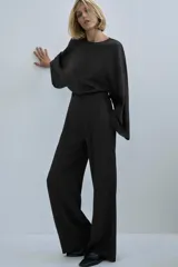 Blusa de viscosa color marrón oscuro, con cuello redondo y manga larga ancha estilo evasé. Presenta un corte recto y cierre de cremallera oculta en la espalda.