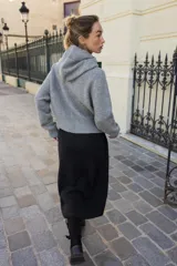 Chaqueta de punto con capucha, manga larga y cierre frontal con cremallera. Presenta un diseño en color beige con un lazo decorativo a contraste en color marrón oscuro en la zona del cuello.