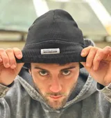 Gorro de lana negro tipo beanie, de tejido acanalado con vuelta y etiqueta frontal bordada de la marca.