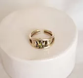 Anillo de bronce con diseño abierto y una zirconia verde engarzada.