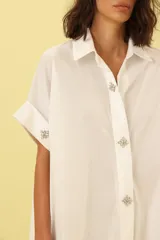 Vestido camisero blanco con botones y corte asimétrico.