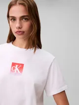 Remera Calvin Klein de algodón color blanco, con cuello redondo, mangas cortas y estampa frontal cuadrada con el monograma cK en tonos degradados de rojo y rosado.