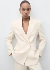 Chaqueta de traje color beige, con cuello de solapa, cierre cruzado con un botón y bolsillos con solapa en los laterales y en el pecho.
