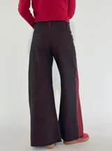 Pantalón de denim gris oscuro con paneles laterales en color bordó y corte acampanado.