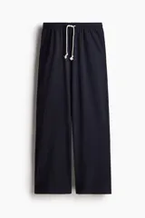 Pantalón jogging de corte amplio confeccionado en punto de algodón suave, con cintura elástica ajustable mediante cordón y bolsillos laterales al bies.