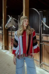 Sweater tejido en hilado 100% algodón con diseño a rayas verticales en tonos rojo, blanco, marrón y negro. Presenta flecos en el ruedo y bordados en el escote.