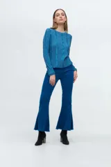 Pantalón de pana tiro alto con corte flare y ruedo desflecado. Presenta costuras verticales decorativas en el frente y cierre lateral.