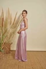 Vestido largo de fiesta en tejido metalizado color rosado, con diseño de un solo hombro y abertura lateral en la cintura.