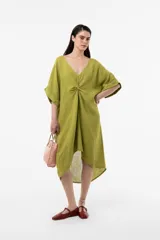 Vestido midi verde lima, de corte amplio y silueta asimétrica. Cuenta con escote en V y un detalle fruncido con nudo en el centro del pecho que genera movimiento en la caída. Sus mangas son cortas y holgadas.