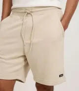 Bermuda masculina de algodón con felpa, color negro, corte slim fit. Presenta cintura elástica con cordón ajustable, bolsillos y etiqueta aplicada.