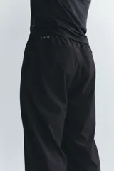 Pantalón deportivo negro de corte estándar y piernas rectas, confeccionado en tejido funcional ripstop con tecnología DryMove™. Cuenta con cintura elástica con cordón de ajuste oculto, bolsillos laterales con cierre y detalles perforados en las piernas.