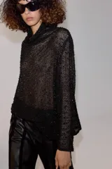 Camisa de hilatura con viscosa color negro, con cuello subido y manga larga ancha. Presenta aplicaciones de abalorios combinados a tono en toda la prenda y bajo recto.