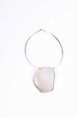 Colgante con aro rígido plateado y dije de nácar irregular.