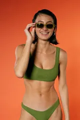 Top de bikini verde militar con textura arrugada, escote amplio y breteles fijos. Incluye bombacha vedetina con frente en V.