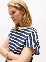 Remera de algodón con diseño de rayas horizontales en azul marino y blanco. Presenta cuello redondo a contraste, mangas tipo kimono y detalle de botones dorados en el hombro.