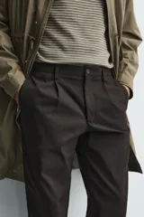 Pantalón de corte regular fit confeccionado en tejido mezcla de algodón. Presenta cintura con detalle de pliegues en el delantero, bolsillos frontales y bolsillos traseros de vivo con botón. Cierre frontal con cremallera y botón.