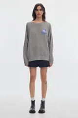 Buzo de felpa sin frisa color terracota con efecto washed, cuello redondo y fit relajado. Presenta un pequeño estampado azul en el pecho.