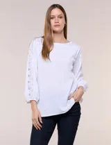 Blusa blanca de silueta holgada confeccionada en tejido texturizado con escote bote y mangas tres cuartos abullonadas con detalles de broderie calado.